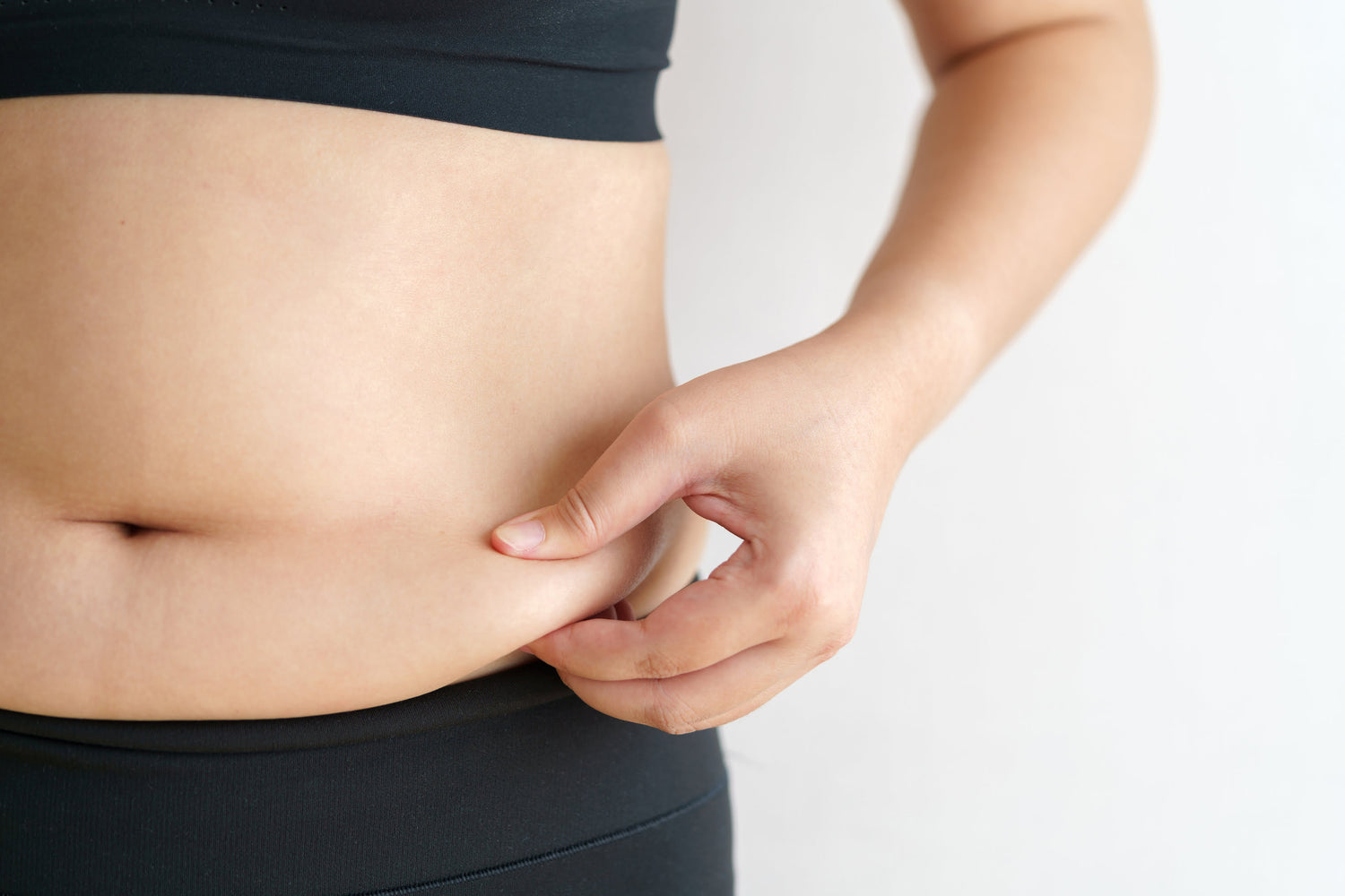 Woman holding her protruding belly, highlighting excess abdominal fat – common concern addressed by SlimFirm Therapy