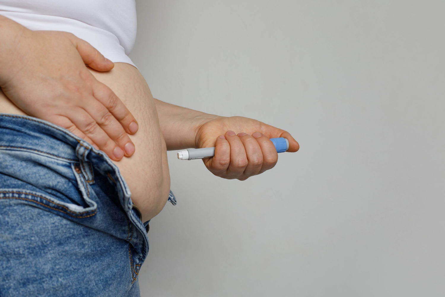Woman injecting a weight-loss medication into her abdomen – close-up view of self-administered subcutaneous injection, typically used for Wegovy