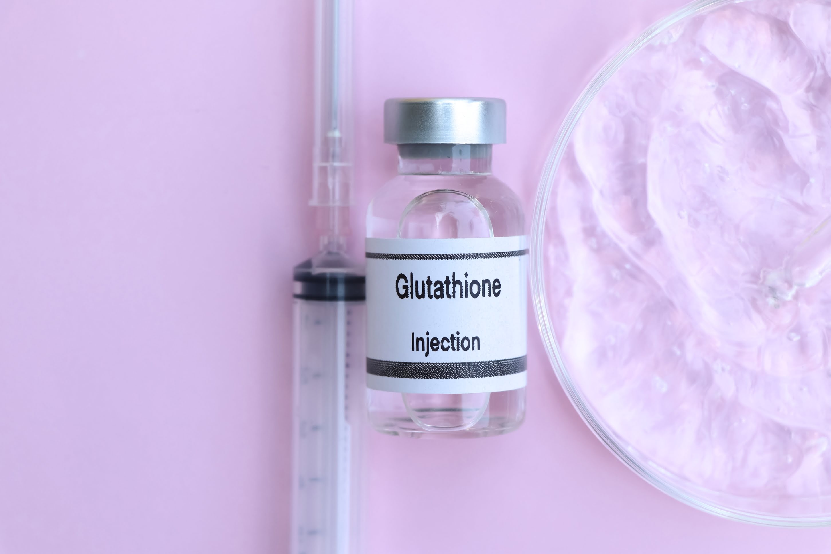 Single ampoule labeled Glutathione next to a sterile syringe on a clean surface, representing antioxidant therapy for detoxification, immune boost, and skin-brightening benefits