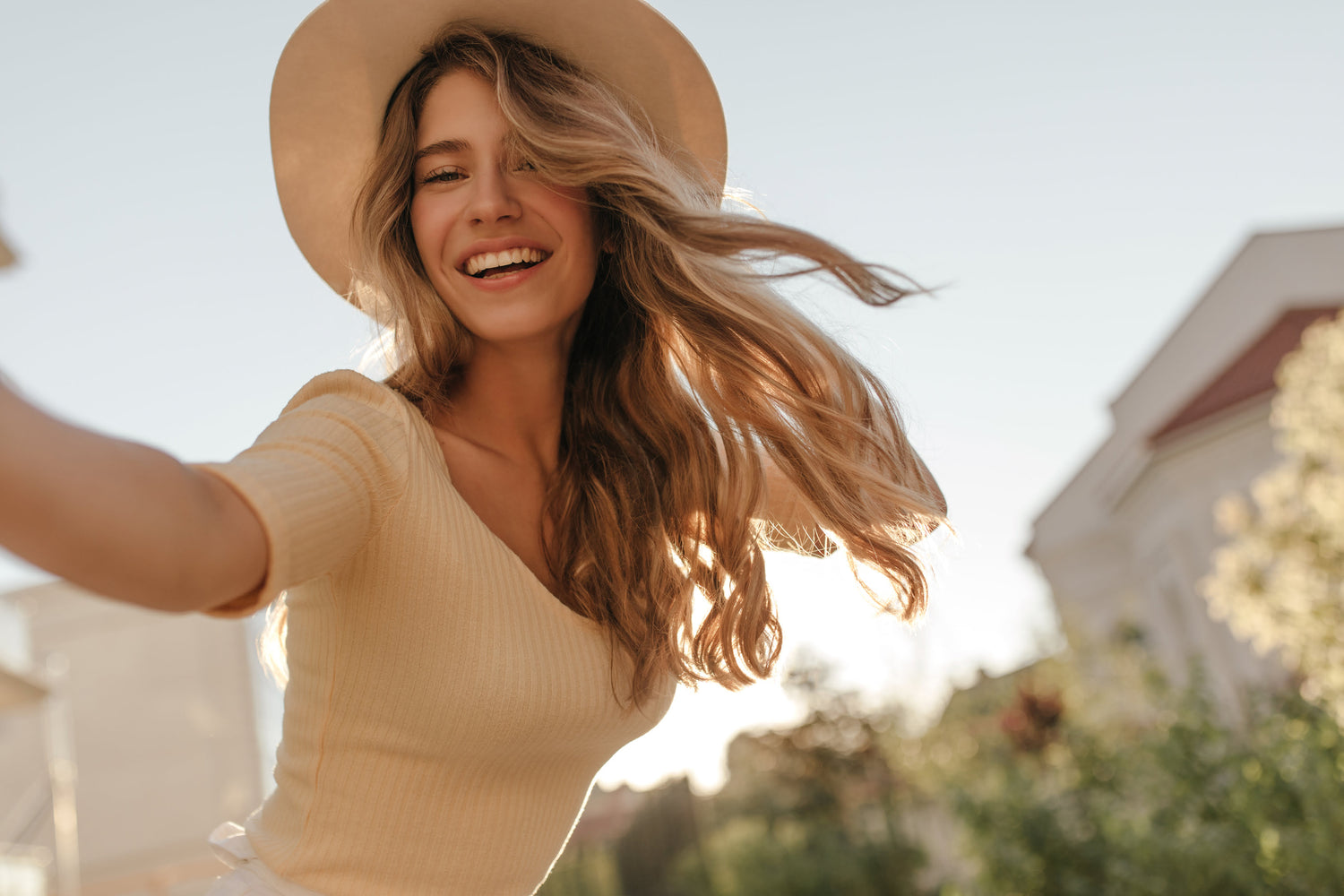 Smiling woman taking a selfie outside in natural daylight, wearing casual stylish clothes, radiating confidence and well-being after a non-invasive pelvic health treatment.