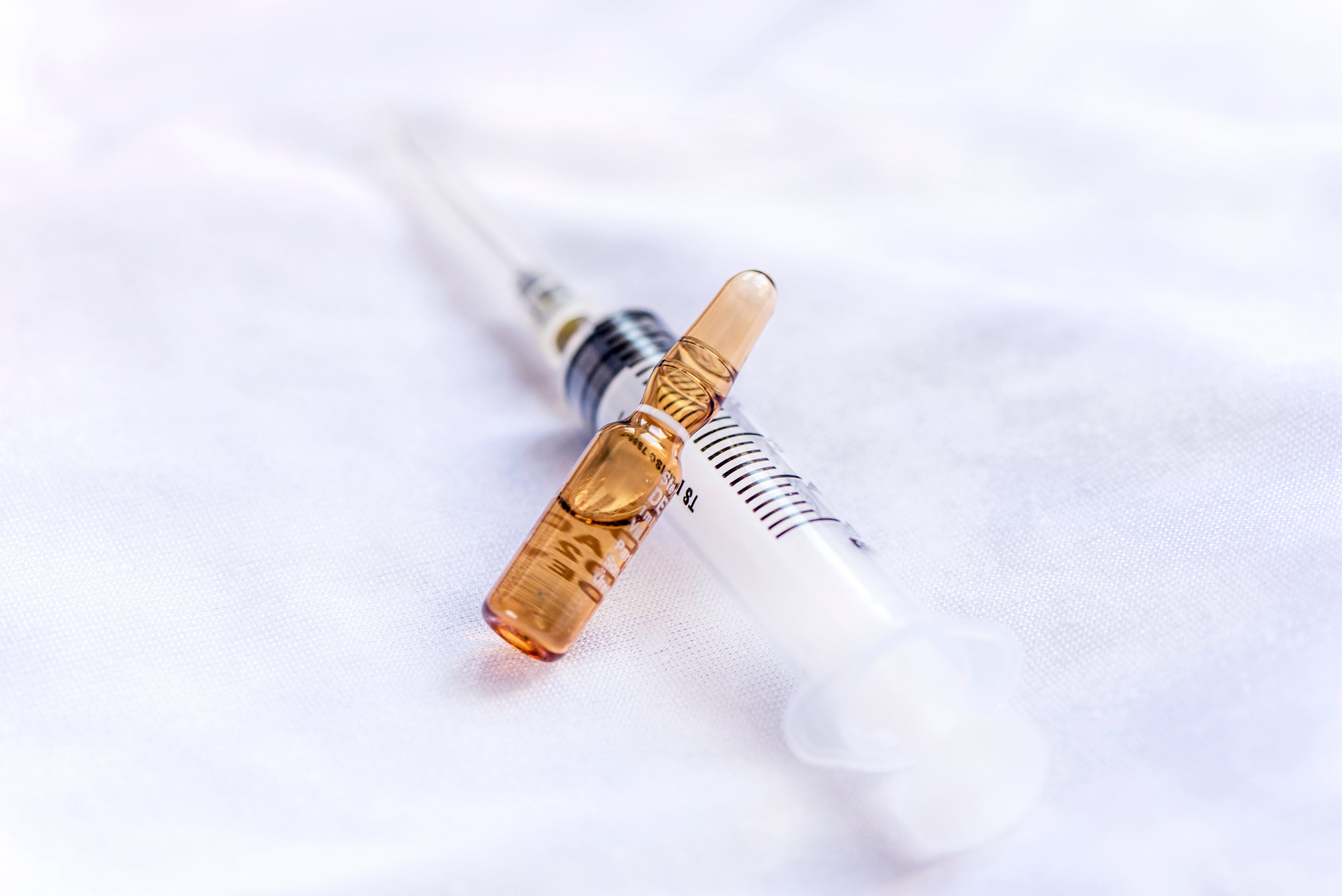 Ampoule labeled Vitamin D3 alongside a medical syringe on a neutral background, symbolising injectable therapy for bone strength, immune support, and treatment of vitamin D deficiency.