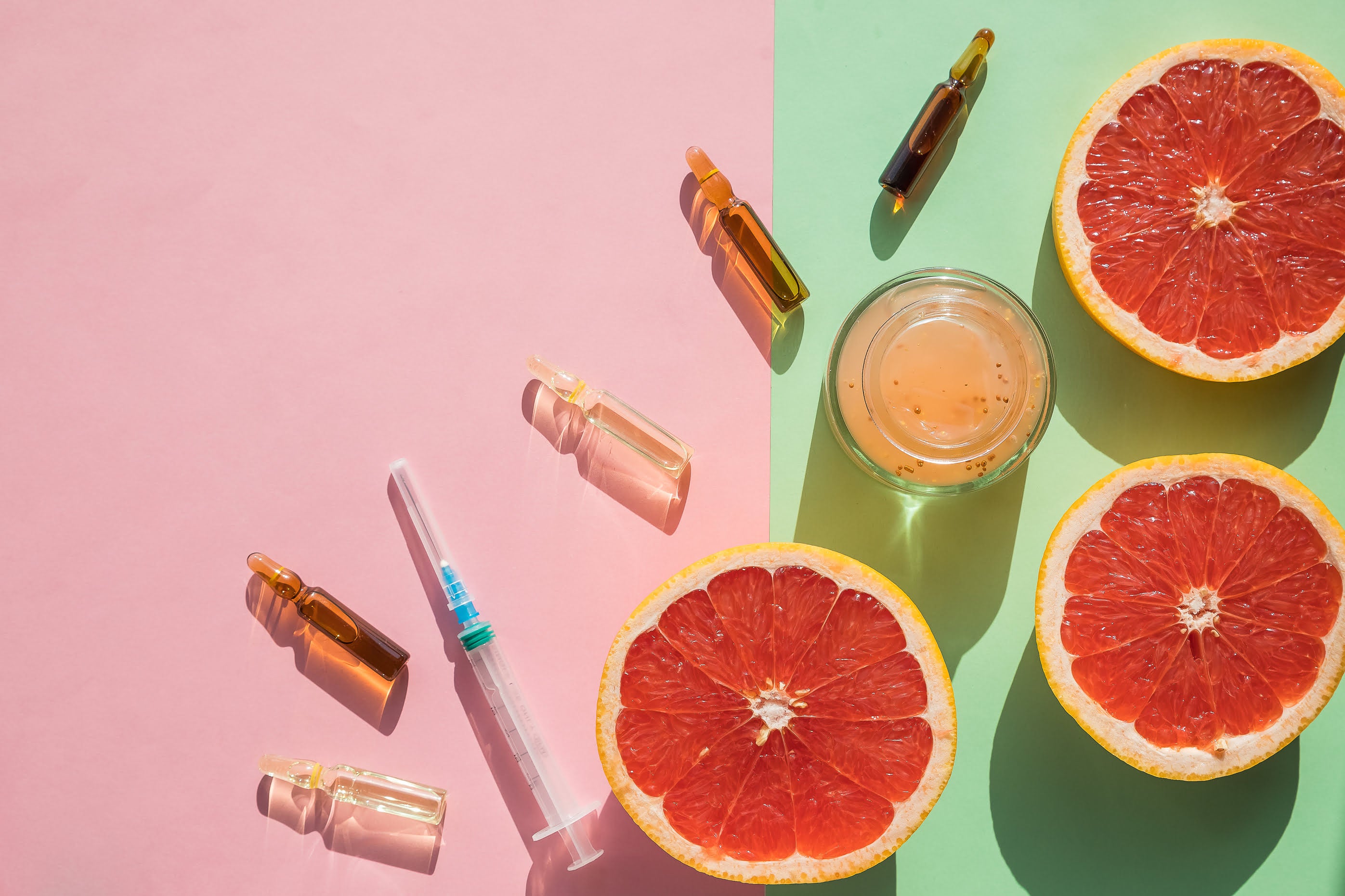 Multiple vitamin ampoules arranged with fresh fruits like oranges and berries, symbolising nutrient-rich intramuscular therapy for enhanced absorption, energy, skin health, and immune support