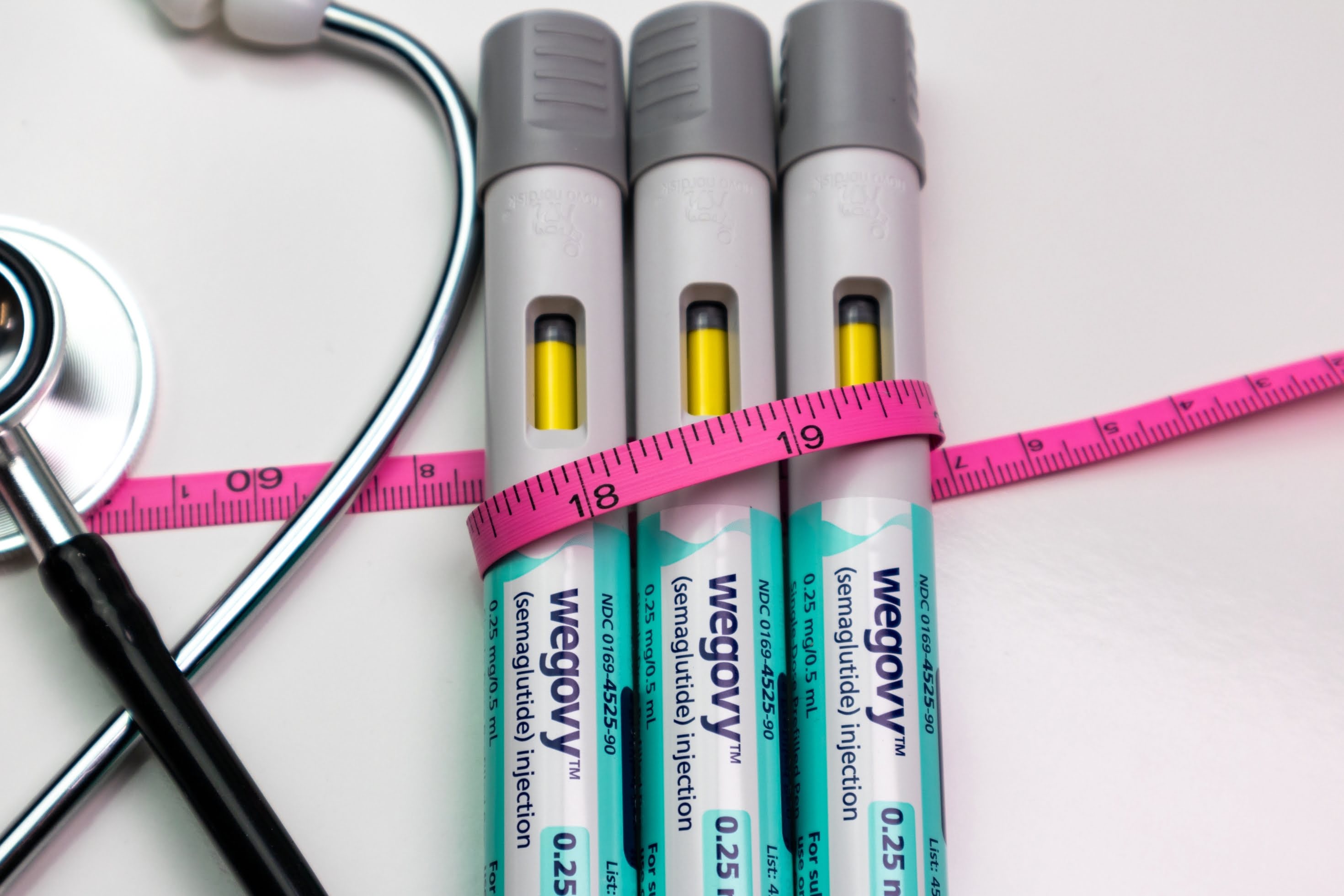 Wegovy weight-loss injection pen placed next to a measuring tape – symbolising medical approach to reducing body measurements and managing obesity